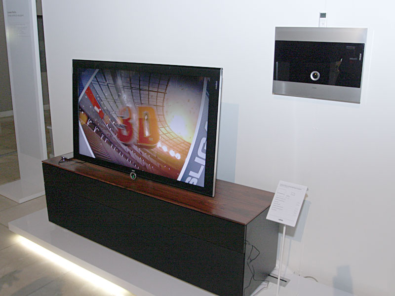 デザイン性の高い家電で知られる独LOEWE(レーベ)は、フレームシーケンシャル方式の3D対応テレビ「Individual 46 Compose 3D」(写真左/5,100ユーロ)を中心に展示。アクティブシャッターの3Dメガネ(750ユーロ)や、ヤマハと共同開発した専用フロントサラウンドスピーカーの「サウンドプロジェクター」(1,600ユーロ)、AVラック、サブウーファ、iPodドック搭載のメディアセンターなどと組み合わせて紹介した。このテレビ「Individual」の内蔵HDDで録画した番組を、LAN経由で32型テレビ「Art 32」(写真右/2,400ユーロ)から視聴できるデモも